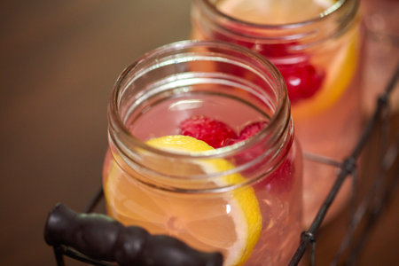 Raspberry lemonade in drinking mason jars on a wood table.の写真素材