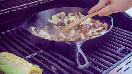 Step by step. Grilled mushrooms and onions in cast iron frying pan on outdoor gas grill.の写真素材
