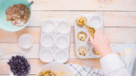 Scooping blueberry muffin batter into metal muffin pan.の写真素材
