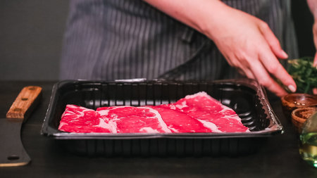 Raw New York strip steaks on a wood cutting board.
