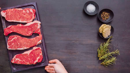 Raw New York strip steaks on a wood cutting board.の写真素材