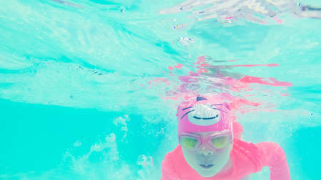 Little girl having fun swimming under the water in outdoor pool.の写真素材