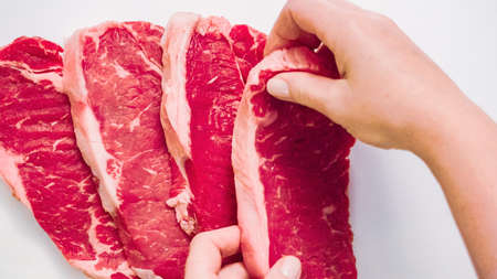 Raw New York strip steaks on a wood cutting board.の写真素材