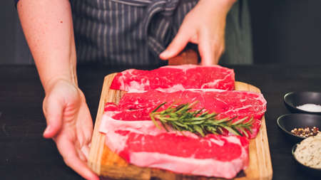 Raw New York strip steaks on a wood cutting board.の写真素材