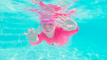 Little girl having fun swimming under the water in outdoor pool.の写真素材