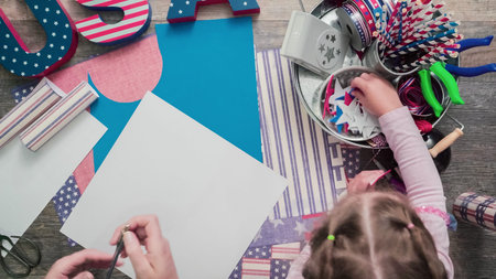 Mother and daughter making paper firecrackers fro July 4th celebration.