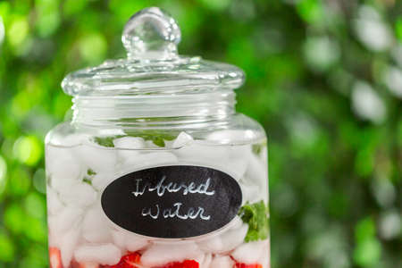 Infused water with organic strawberries, kiwi and fresh mint in glass beverage drink dispenser.の写真素材