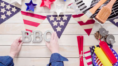 Metal BBQ sign with July 4th decorations on a wood boards.の写真素材