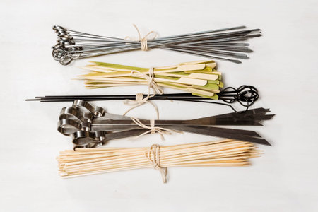 Steel and wood skewers on a white painted wood background.の写真素材