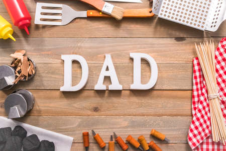 Dad sign for Father's Day with grilling tools on wood background.の写真素材