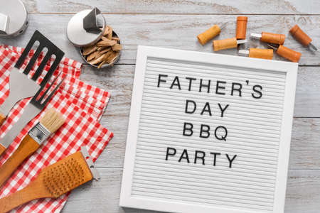 Father's Day BBQ Party sign on a white memo board with cooking tools.の写真素材