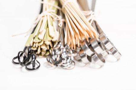Steel and wood skewers on a white painted wood background.