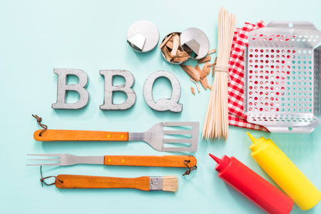 Metal BBQ sign with grilling tools on blue background.の写真素材