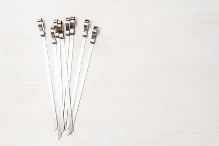 New steel skewers on white wood table.の写真素材