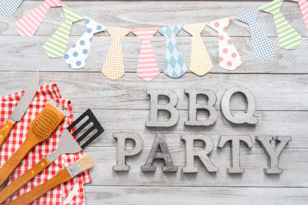 BBQ Party sign with BBQ cooking tools on a wood background.の写真素材