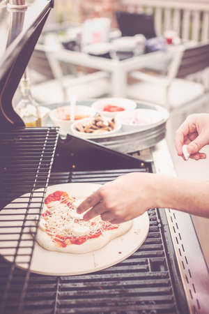 Cooking pizza on outdoor gas grill.の写真素材