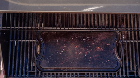 Empty cast iron griddle on outdoor gas grill.