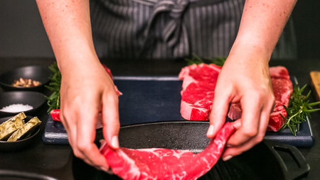 Raw New York strip steaks in cast iron frying pan.