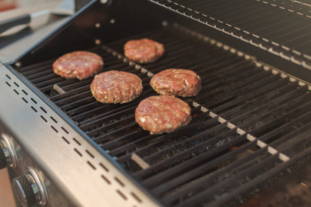 Grilling classic burgers on outdoor gas grill in the Summer.