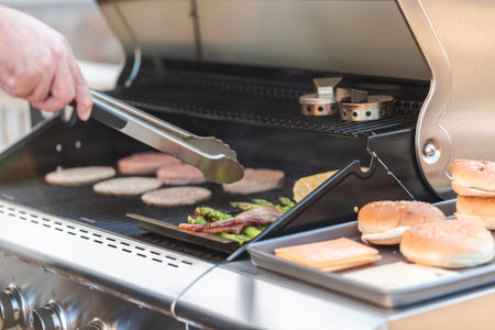 Step by step. Cooking hamburgers on outdoor gas grill in the Summer.