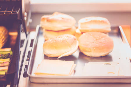 Step by step. Burger buns on the tray next to outdoor gas grill.の写真素材