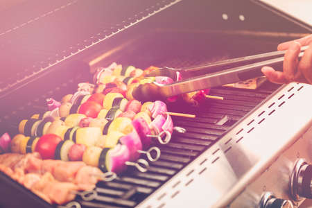 Step by step. Grilling veggie skewers and chicken kebabs on outdoor gas grill.の写真素材