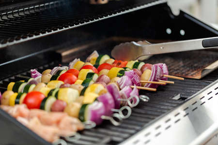 Step by step. Grilling veggie skewers and chicken kebabs on outdoor gas grill.の写真素材