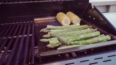 Step by step. Grilling asparagus on outdoor gas grill.