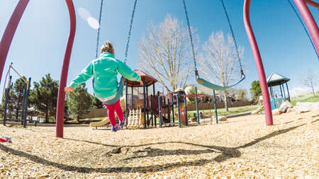 Little girl playing on outdoor childrens playground in suburbs.の写真素材