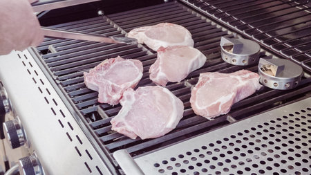 Cooking pork chops with pineapples on gas grill in the Summer.