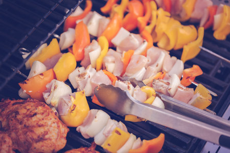 Step by step. Cooking chicken shish kabobs with bell peppers and yellow onions on outdoor gas grill.
