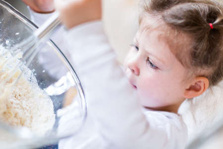 Little girl mixing dough for home made pepperoni pizza.の写真素材