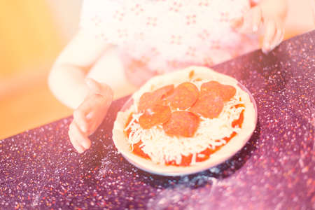 Little girl making home made small pepperoni pizzas.の写真素材