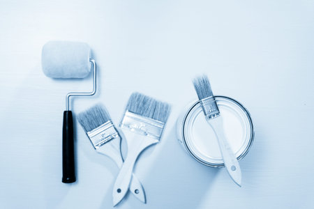 Top view of metal paint can and paint brushes on painted surface.