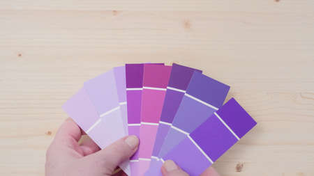 Variety of paint swatches with shades of purple pain on unfinished wooden background.の写真素材
