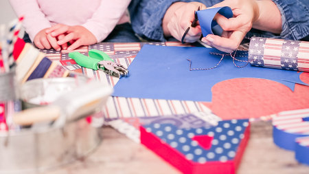 Step by step. Mother and daughter making paper firecrackers for July 4th celebration.