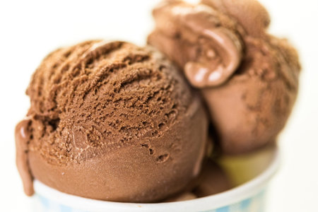 Chocolate ice cream scoops in paper cup.