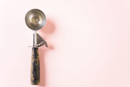 Empty metal ice cream scoop on pink background.