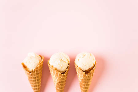 Waffle ice cream cones with plate of ice cream scoops on a pink background.の写真素材