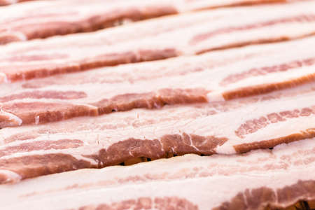 Raw bacon strips on a baking sheet.の写真素材