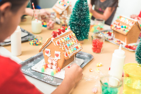 Kids decorating small gingerbread houses at the Christmas craft party.