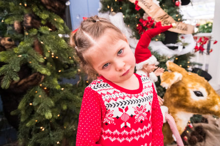 Little girl in red dress on Christmas tree farm.