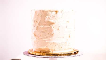 Baker frosting pink and purple cake with a white buttercream icing.