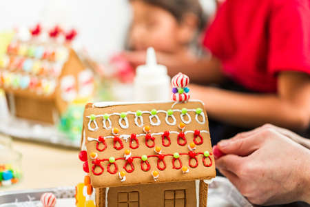 Kids decorating small gingerbread houses at the Christmas craft party.の写真素材