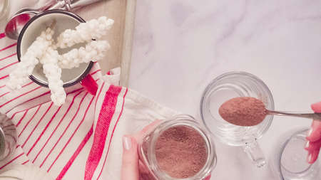 Flat lay. Putting hot chocolate mix into glass cup.の写真素材