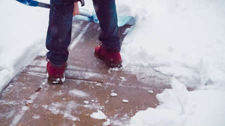 Young man shoveling snow from driveway.の写真素材