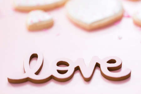 LOVE sign with heart shaped sugar cookies on a pink background.の写真素材