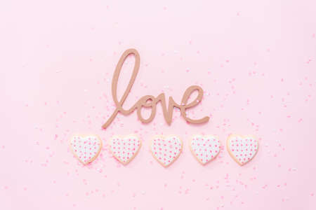 Flat lay. Heart shaped sugar cookies decorated with royal icing for Valentine's Day on a pink background.の写真素材