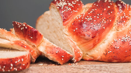 Step by step. Slicing freshly baked shallah bread with sesame and poppy seeds.