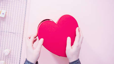 Flat lay. Packing heart shaped sugar cookies decorated with royal icing into the gift box.の写真素材